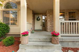 Entrance to property with covered porch, stucco siding, and stone siding