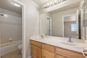 Bathroom with double vanity, tile patterned flooring, toilet, and bathing tub / shower combination