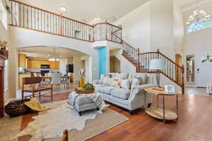 Living area with a chandelier, a towering ceiling, arched walkways, stairway, and healthy amount of natural light