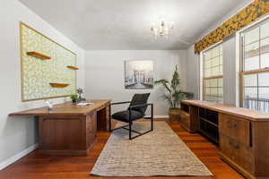 Office area with a chandelier, baseboards, and dark wood-type flooring