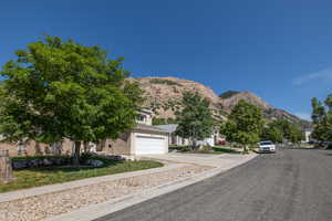View of asphalt road with a mountain view, sidewalks, and curbs