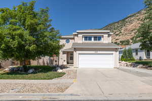 View of front of house with stucco siding, a garage, concrete driveway, and a mountain view