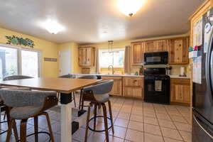 Kitchen with black appliances, light countertops, a sink, and light tile patterned floors