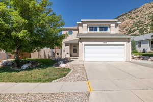 View of front of property featuring concrete driveway, stucco siding, an attached garage, and a mountain view