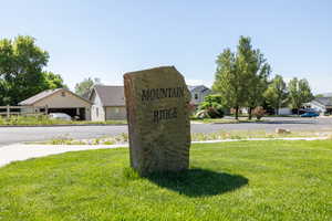 Community sign featuring a yard and a residential view