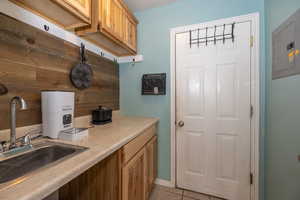 Kitchen featuring a sink, electric panel, light countertops, and light tile patterned floors