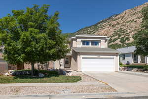 View of front of home with a mountain view, stucco siding, concrete driveway, and an attached garage