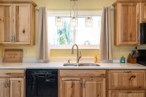 Kitchen with dishwasher, a sink, light countertops, and range