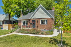 Bungalow with a chimney, brick siding, and roof with shingles