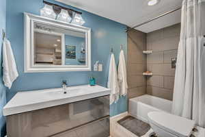 Bathroom with shower / tub combo, vanity, toilet, recessed lighting, and baseboards