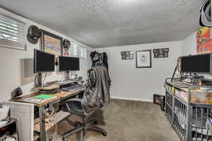 Carpeted office space with baseboards and a textured ceiling