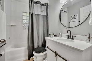 Full bath with toilet, shower / bath combo with shower curtain, and vanity