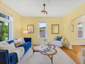 Living room with wood finished floors, baseboards, arched walkways, and a chandelier