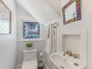 Half bath with toilet, baseboards, and vaulted ceiling
