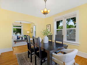 Dining room with a chandelier, arched walkways, wood finished floors, and baseboards