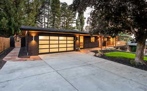View of front facade featuring a garage, driveway, a gate, and brick siding