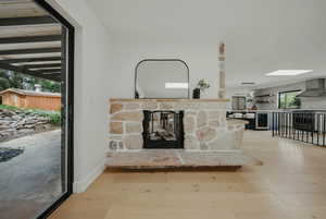 Unfurnished living room with wood finished floors, a fireplace, a sink, and a skylight