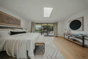 Bedroom featuring a skylight, access to exterior, and light wood-type flooring