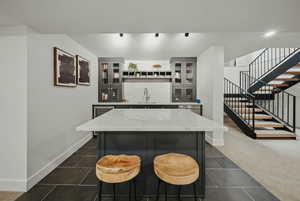 Recreation room featuring baseboards, bar with sink, and dark tile patterned floors