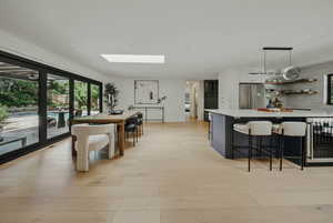 Dining area with wine cooler, light wood-style floors, and a skylight