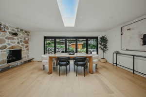 Dining area with plenty of natural light, wood finished floors, and a fireplace