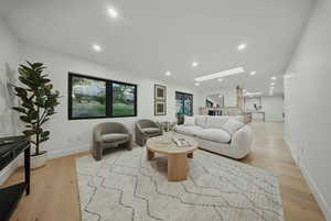 Living area with a skylight, light wood-style flooring, recessed lighting, and baseboards