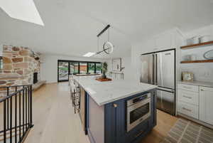 Kitchen featuring high end refrigerator, open shelves, light wood-style flooring, and white cabinetry