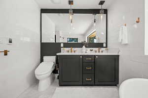 Full bathroom with double vanity, toilet, tile walls, and a freestanding bath