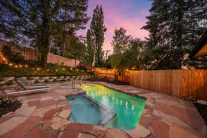 View of swimming pool featuring a pool with connected hot tub, a fenced backyard, and a patio area