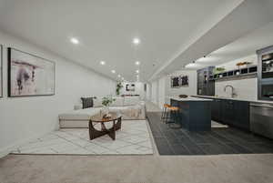 Living area with bar with sink, recessed lighting, baseboards, and dark tile patterned floors