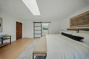 Bedroom with light wood finished floors and a skylight