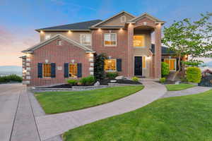 Traditional-style house featuring stucco siding, a front lawn, and brick siding