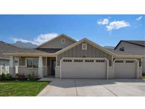 Craftsman-style home featuring an attached garage, concrete driveway, board and batten siding, brick siding, and a front lawn
