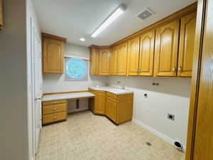 Laundry area with cabinet space, hookup for an electric dryer, craft desk, built-in ironing board, space for additional refrigerator or freezer.