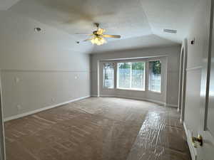 Primary bedroom with high ceiling, bay window and ceiling fan.