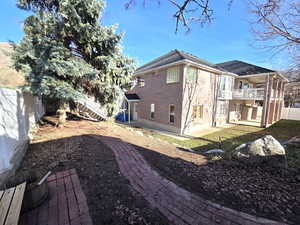 View of home's brick exterior featuring a covered deck, a fenced backyard, and covered patio area.