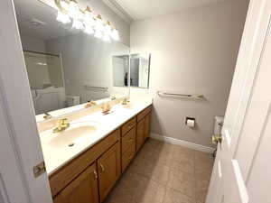 Main level bathroom with dual sink and tile floor.