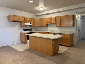 Full basement Kitchen featuring light countertops, light colored carpet, white range with electric cooktop, brown cabinetry, and recessed lighting