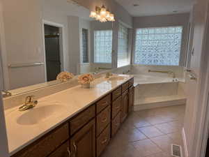Primary bathroom with dual sink vanity, jetted tub, separate shower and tile floor.