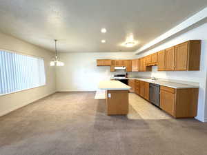 Kitchen with stainless steel dishwasher, stove, island and dining area.