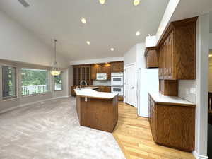 Vaulted kitchen with dual ovens and built in glass cabinets and hardwood floor.