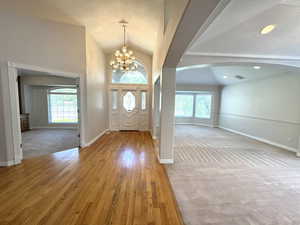 Foyer featuring lofted ceiling, plenty of natural light, arched walkways, and hardwood floors.