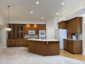 Vaulted kitchen with dual ovens and built in glass cabinets and hardwood floor.