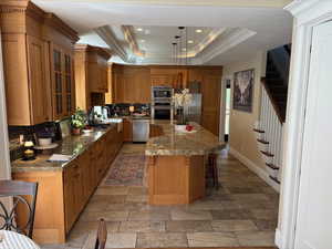 Coved ceiling in kitchen with canned lights and hanging light fixtures over the breakfast bar