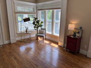 Living area off front entry with large windows that look out to the park and lovely hardwoods