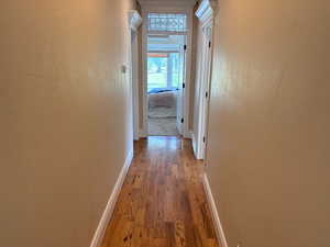 Corridor leading to primary bed up with wood finished floors and baseboards