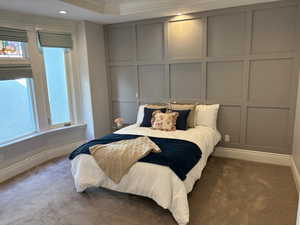 Primary bedroom on the main with a bay window, recessed lighting, custom paneling and crown moldings