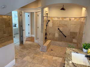 Primary bath up featuring a huge no-step custom tiled shower and stone tile flooring
