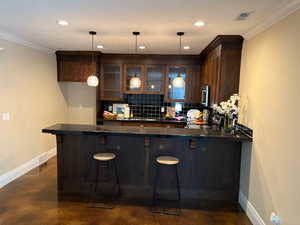 Full kitchen or wet bar with pendant lighting, and ornamental molding