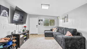 Living area with light carpet, lofted ceiling, and baseboards